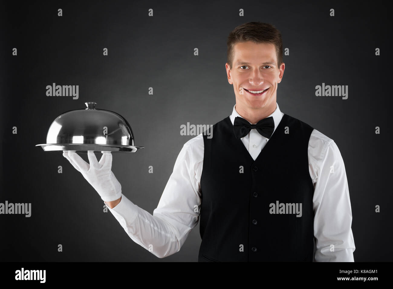 Portrait von Happy Kellner Holding Edelstahl Cloche über Fach Stockfoto