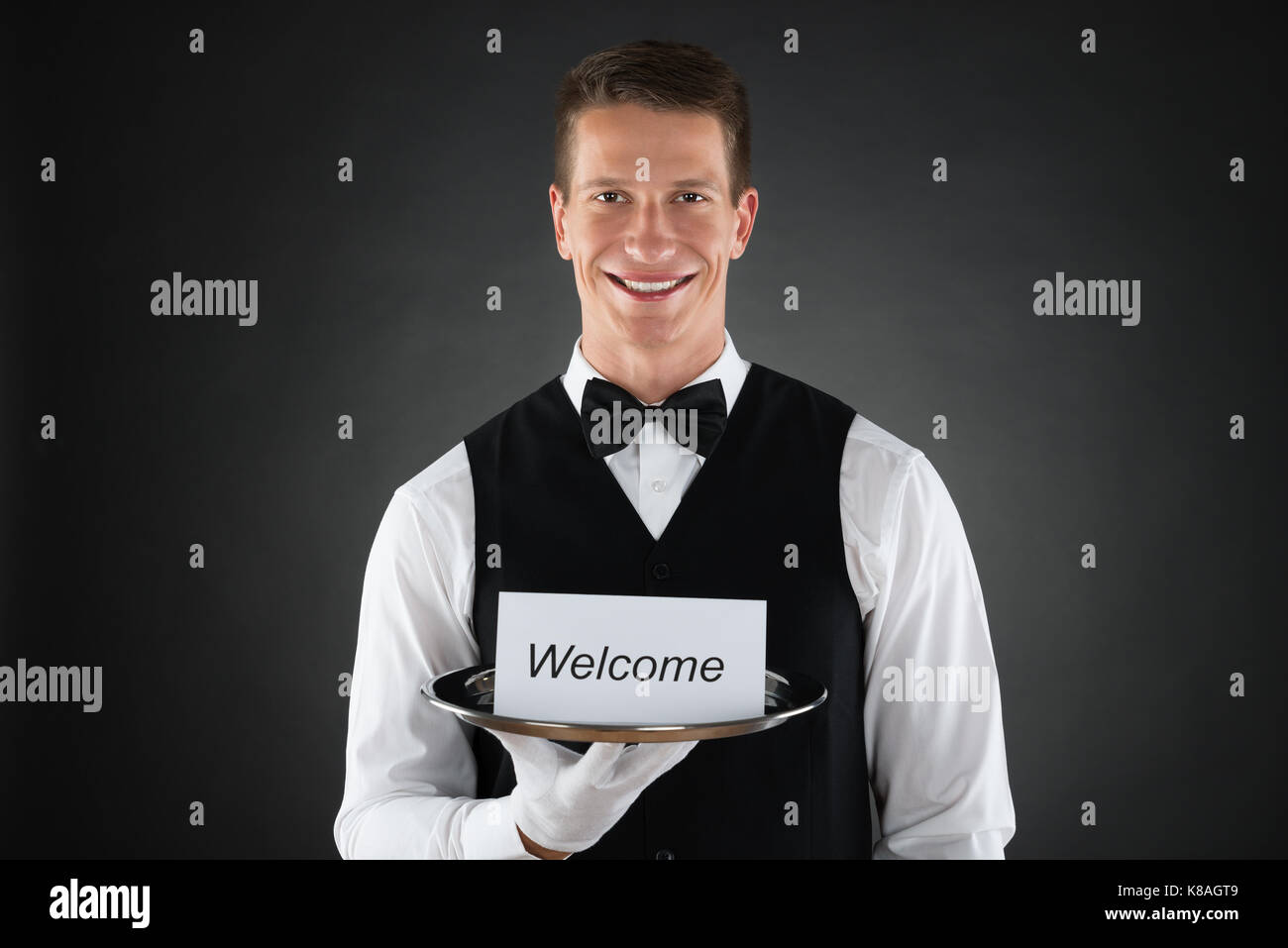 Porträt der jungen Kellner Halteplatte mit Willkommen Text auf der Karte Stockfoto