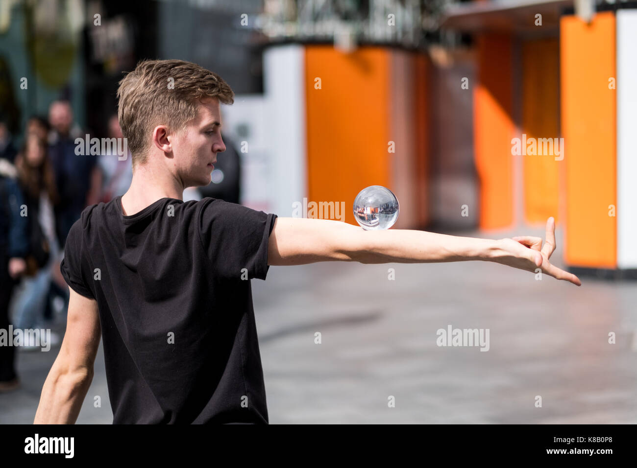 Eine street Entertainer gleicht einem Glas Kugel auf seinem Arm in Londons geschäftigen Leicester Square Stockfoto