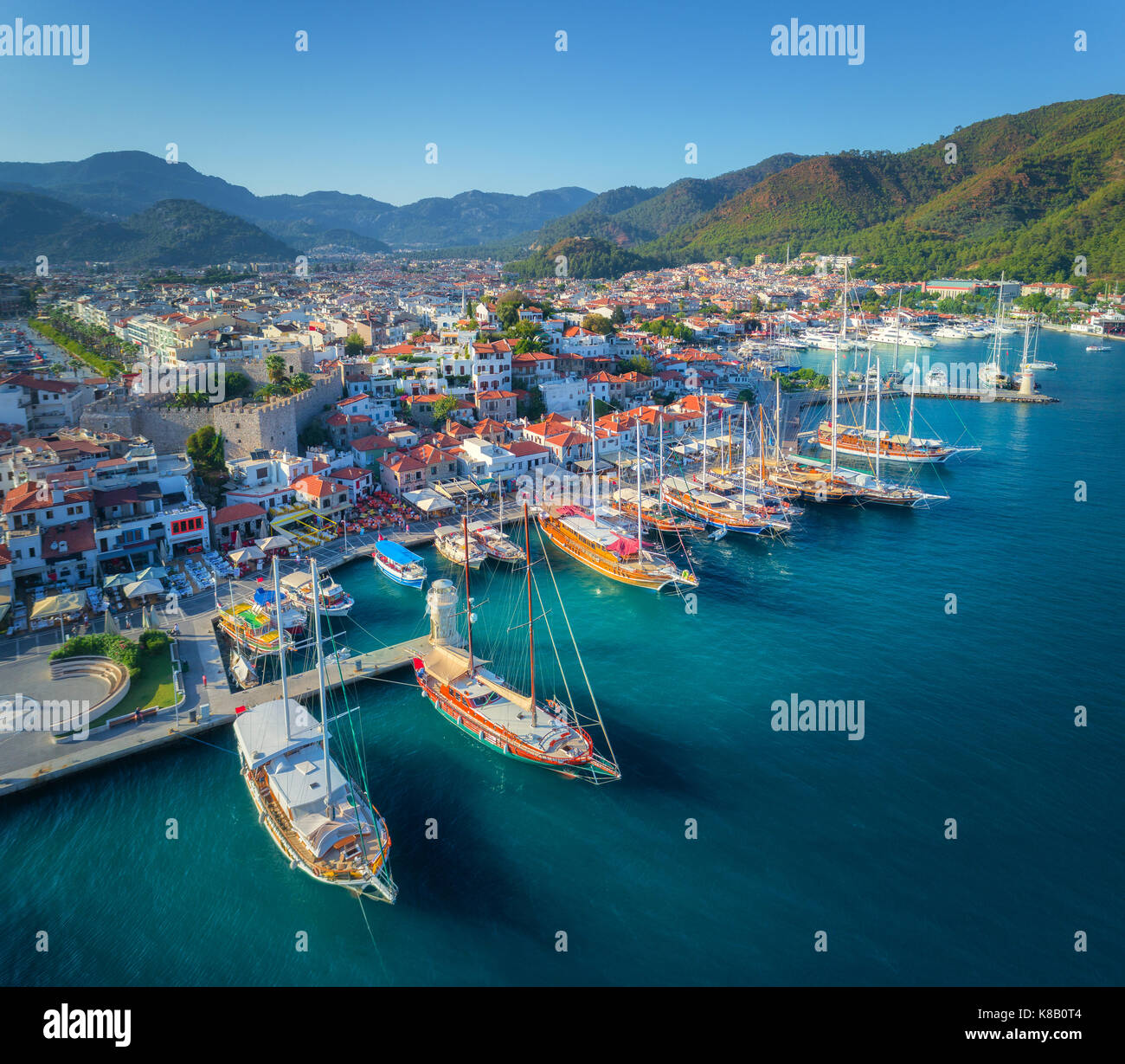 Luftaufnahme der Boote und der schönen Architektur bei Sonnenuntergang in Marmaris, Türkei. Bunte Landschaft mit Yachten in der Marina Bay, Meer, Stadt, in den Bergen. Top Stockfoto