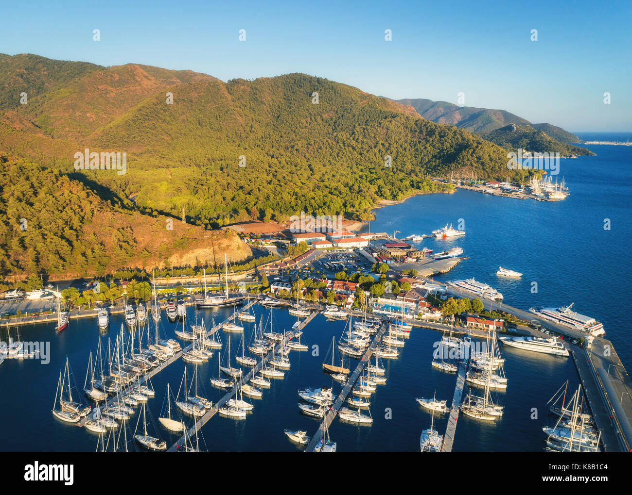 Luftaufnahme der Boote und der schönen Berge bei Sonnenuntergang in Marmaris, Türkei. Bunte Landschaft mit Yachten in der Marina Bay, See, Stadtzentrum, Wald. Ansicht von oben f Stockfoto