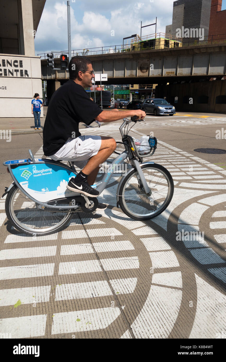 Ein Mann reitet ein Mietfahrrad in der Innenstadt von Pittsburgh, Pennsylvania, USA Stockfoto