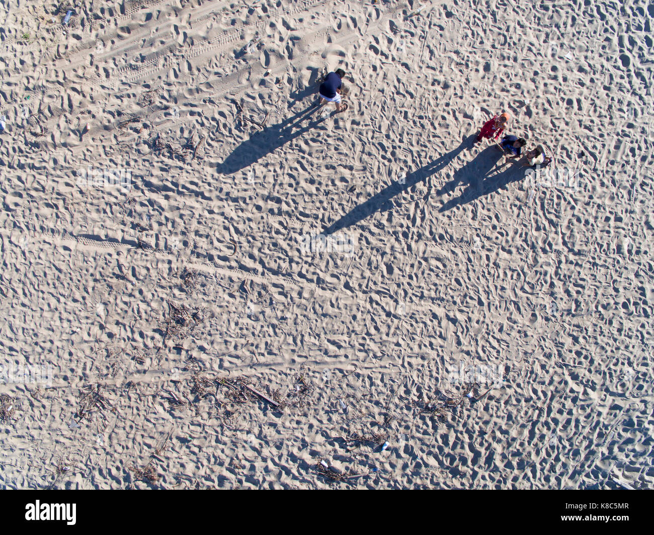 Kinder spielen Sand am Strand mit Schatten Stockfoto