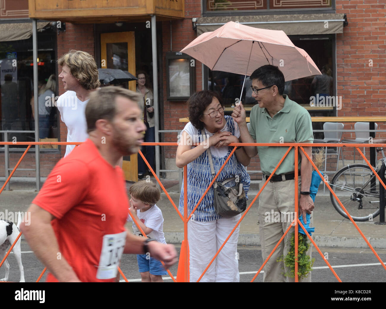 Ein Läufer zeigt Entschlossenheit, wie er das Ende der Pearl Street Meile Rennen in einem leichten Regen als Zuschauer genießen Sie die Veranstaltung in der Innenstadt von Bou nähert sich Stockfoto