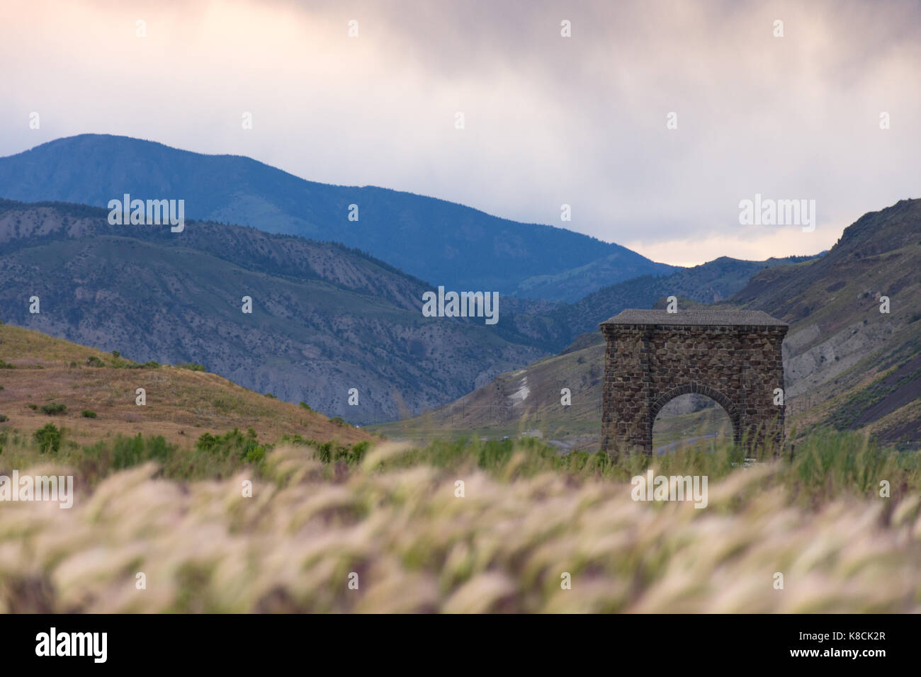 Roosevelt arch am nördlichen Eingang des Yellowstone National Park mit hohen Gras im Vordergrund und die Berge dahinter. Stockfoto