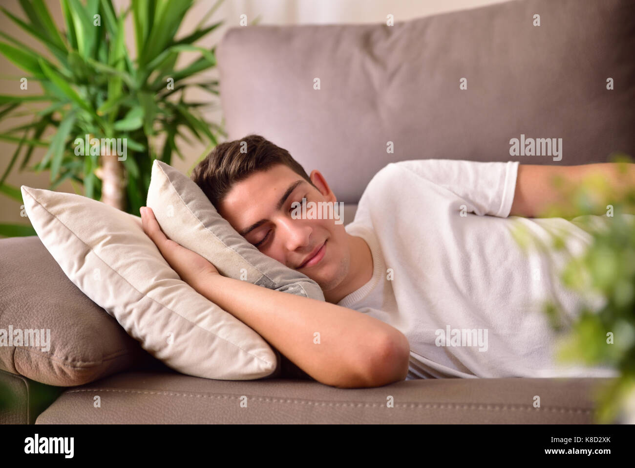 Mann napping glücklich liegen auf einem Sofa mit Kissen zu Hause. Ansicht von vorn Stockfoto