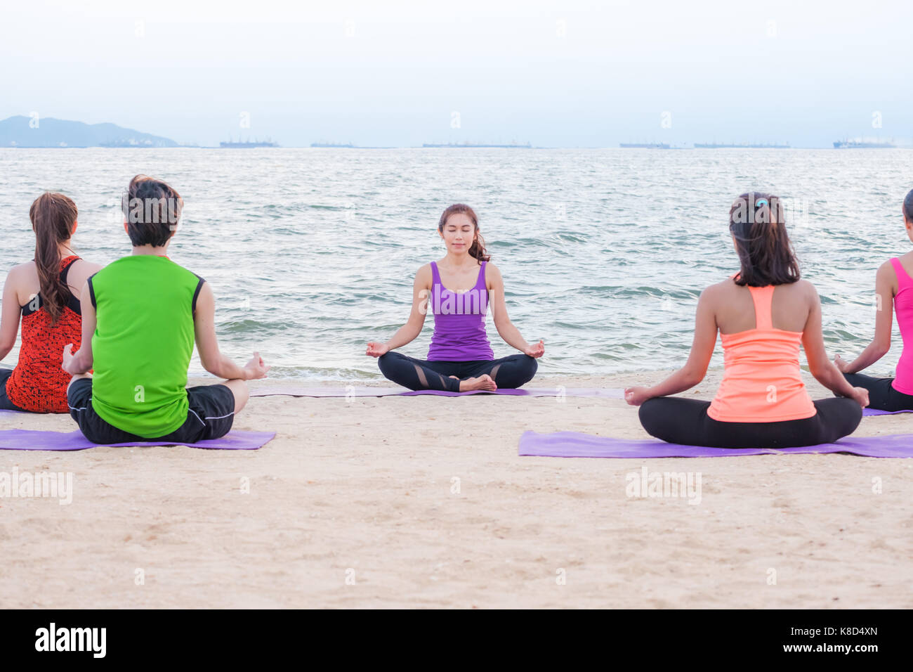 Yoga Ausbildung Klasse am Meer Strand im Sonnenuntergang am Abend, Gruppe von Menschen Lotus tun, wirft mit Clam emotion am Strand entspannen, Meditation, Wellness- und Er Stockfoto