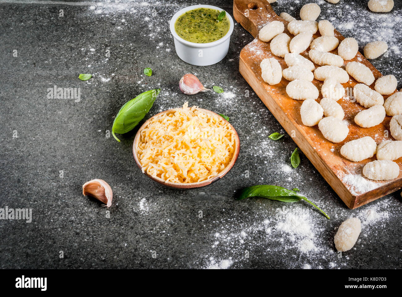 Roh ungekocht Hausgemachte Gnocchi mit Mehl, geriebenen Parmesan, Basilikum und Pesto. Auf konkrete grauer Hintergrund, Kopie Raum Stockfoto