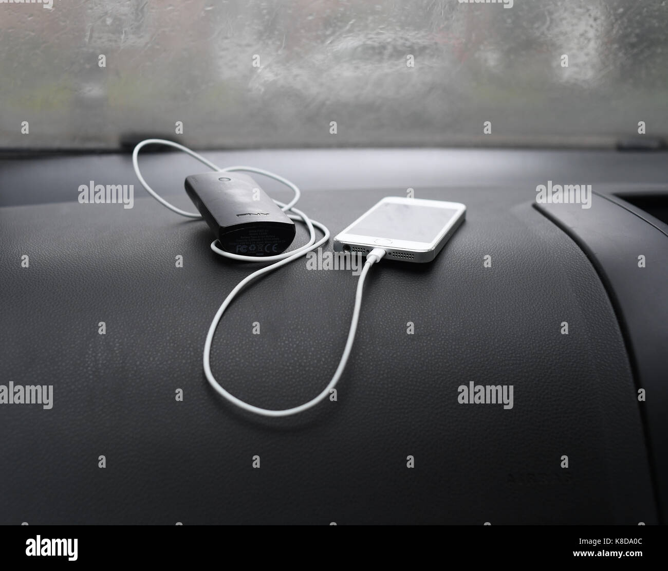 Iphone 5s mit externem Ladegerät am Armaturenbrett des Autos Stockfoto