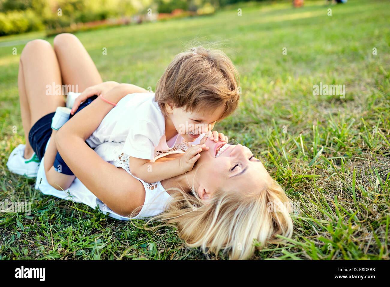 Mutter und Sohn umarmen Spielen auf dem Rasen im Park. Stockfoto