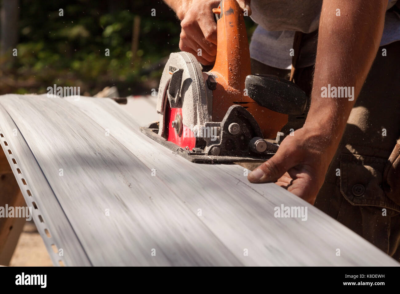Ein Bauarbeiter mit einem Handheld Kreissäge durch Vinylabstellgleis in Ontario, Kanada zu schneiden. Stockfoto