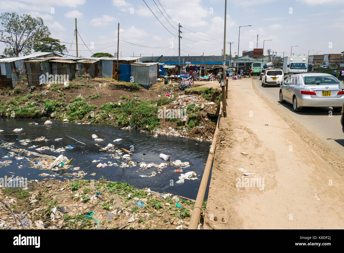 Enterprise Straße Brücke der Ngong Fluss, der mit Müll verunreinigt ist, Kunststoff Abfall und Müll Kreuze, slum Hütten säumen den Fluss, Nairobi, Kenia Stockfoto