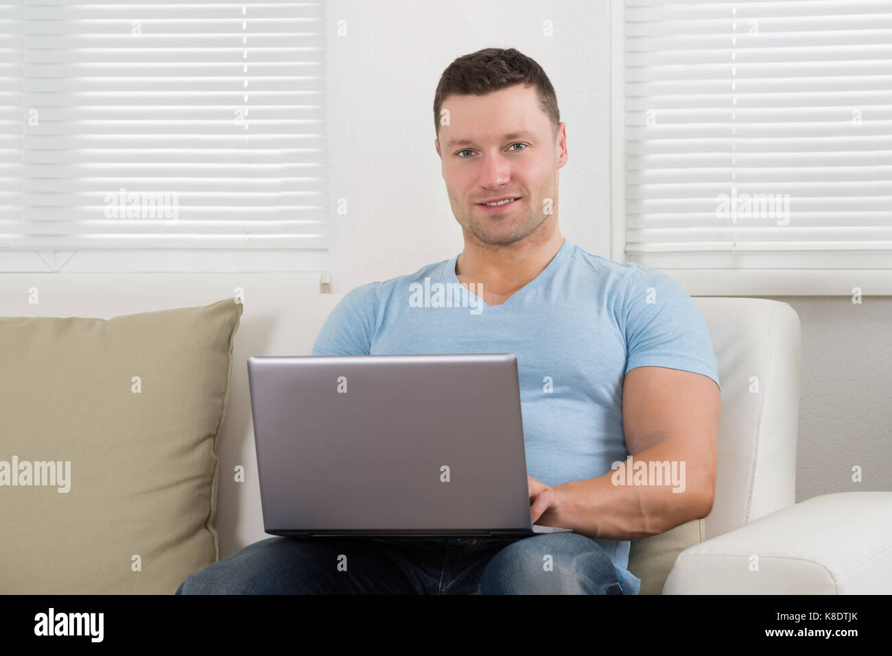 Portrait von stattlichen Mitte der Erwachsenen mit Laptop auf dem Sofa zu Hause Mann Stockfoto