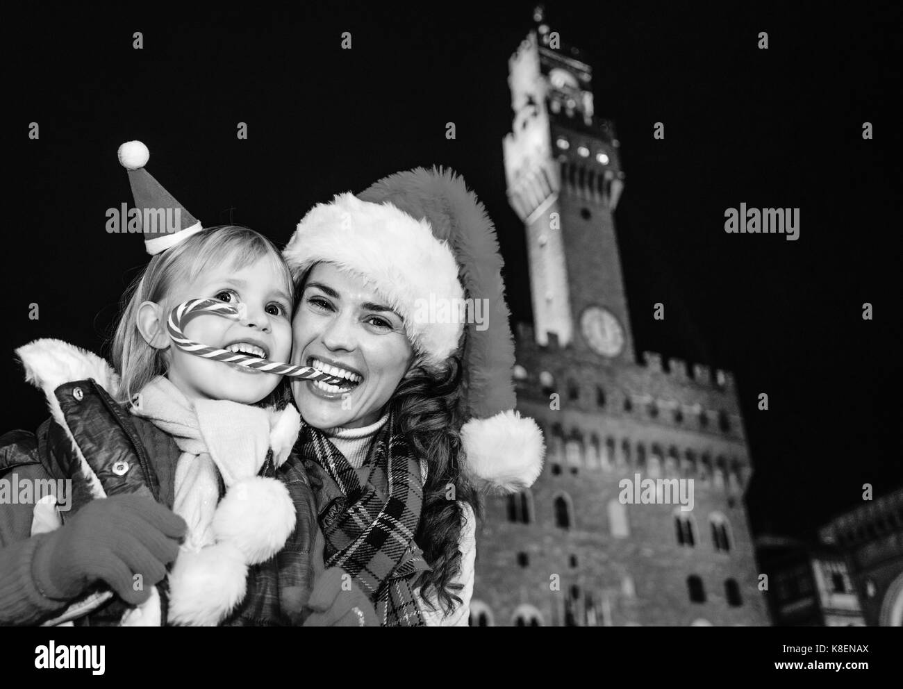 Reise voller Inspiration zur Weihnachtszeit in Florenz. Porträt der glückliche junge Mutter und Kind Reisenden in Weihnachten Hüte gegen Palazzo Vecchio Stockfoto