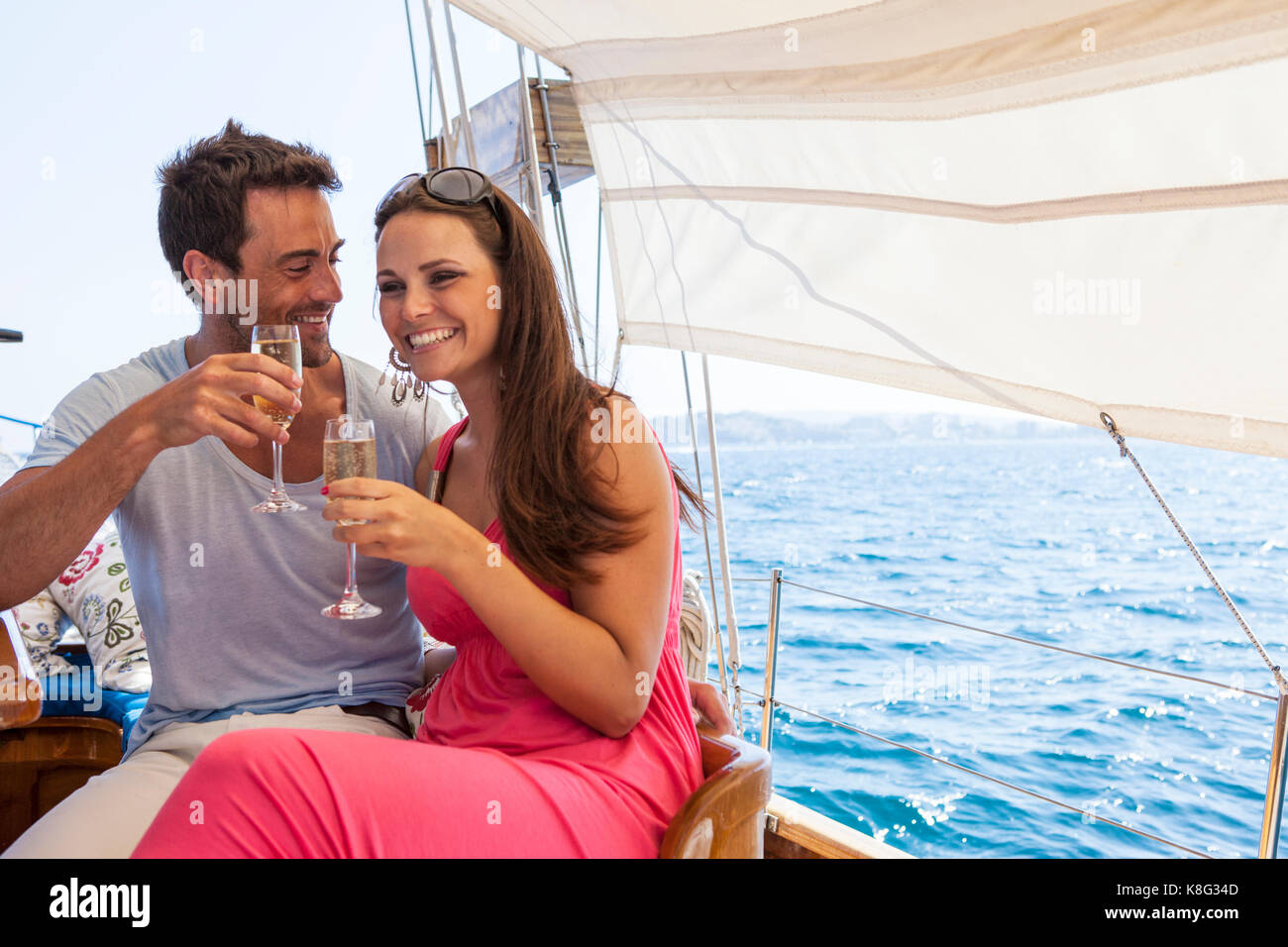 Paar sitzt auf dem Boot, auf dem Wasser, Champagnergläser, lächelnd Stockfoto