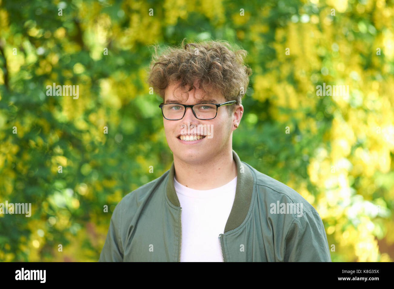 Portrait von Curly blonde junge Mann an der Kamera schaut lächelnd Stockfoto