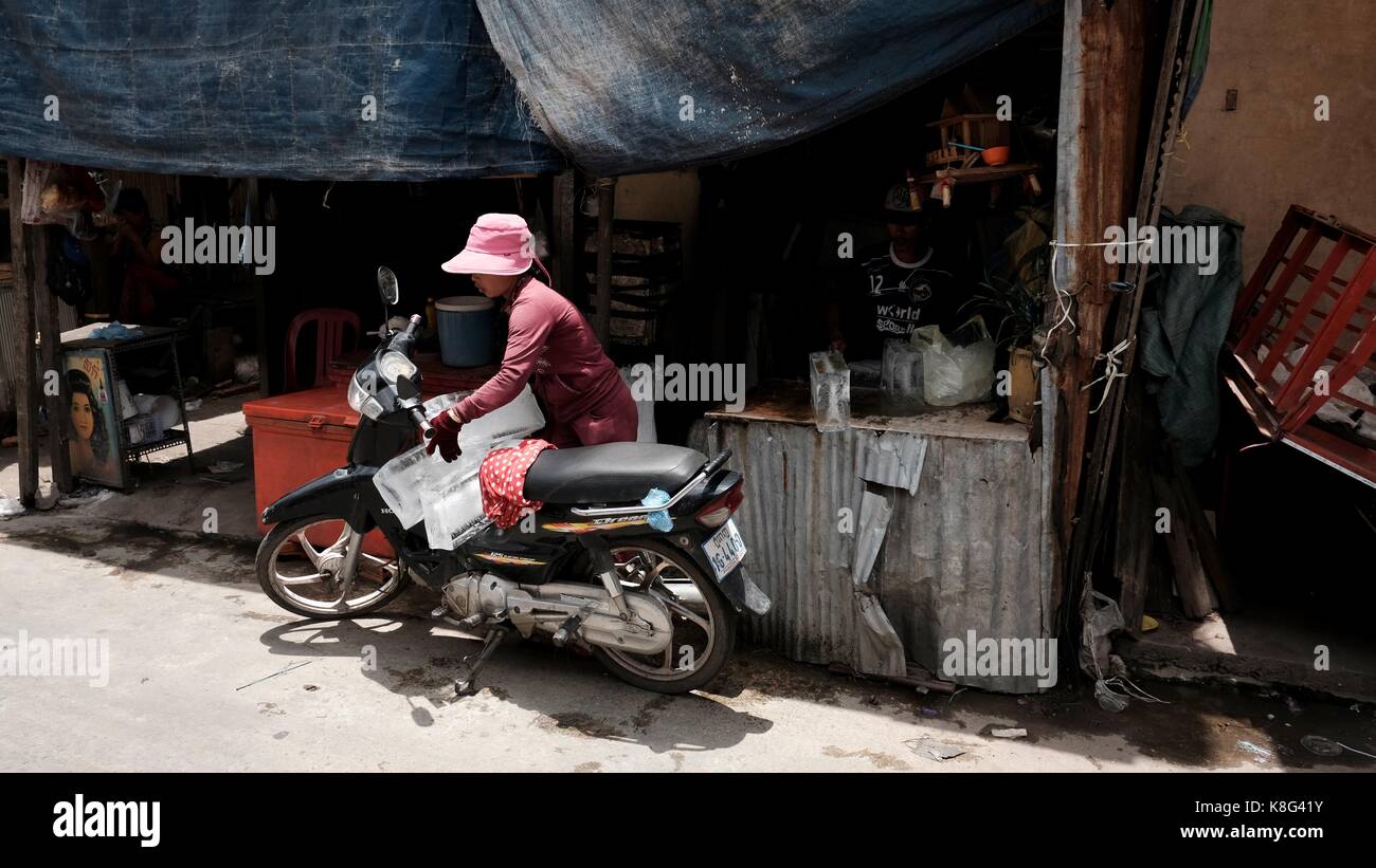 Arme Menschen, die in Holzhütten leben Armut befahl, die Phnom Penh Monivong Bridge Squatter Communities Cambodia Lady in Pink auf dem Moterbike zu verlassen Stockfoto