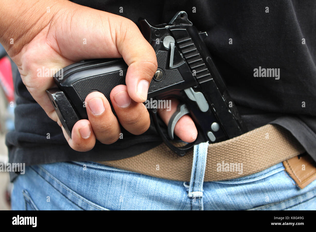 Gangster verbergen seine Waffe hinter seinem Rücken Stockfoto