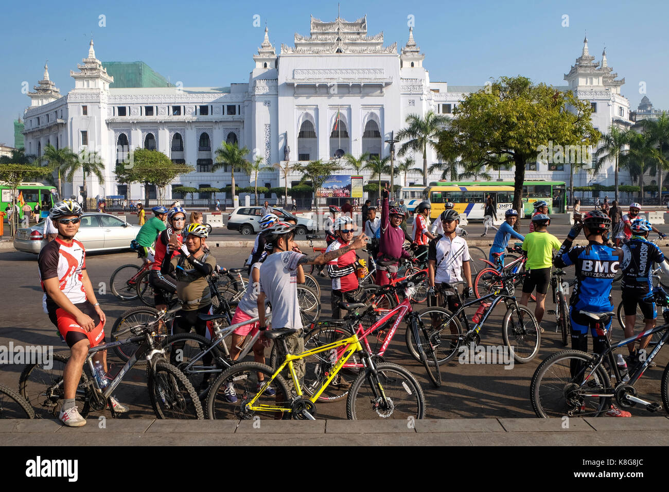 Burma, Myanmar: Kolonialzeit Gebäude in Yangon (früher Rangoon). Gruppe der Radfahrer auf dem Platz vor der weißen Fassade *** Loca der Stadt Halle Stockfoto