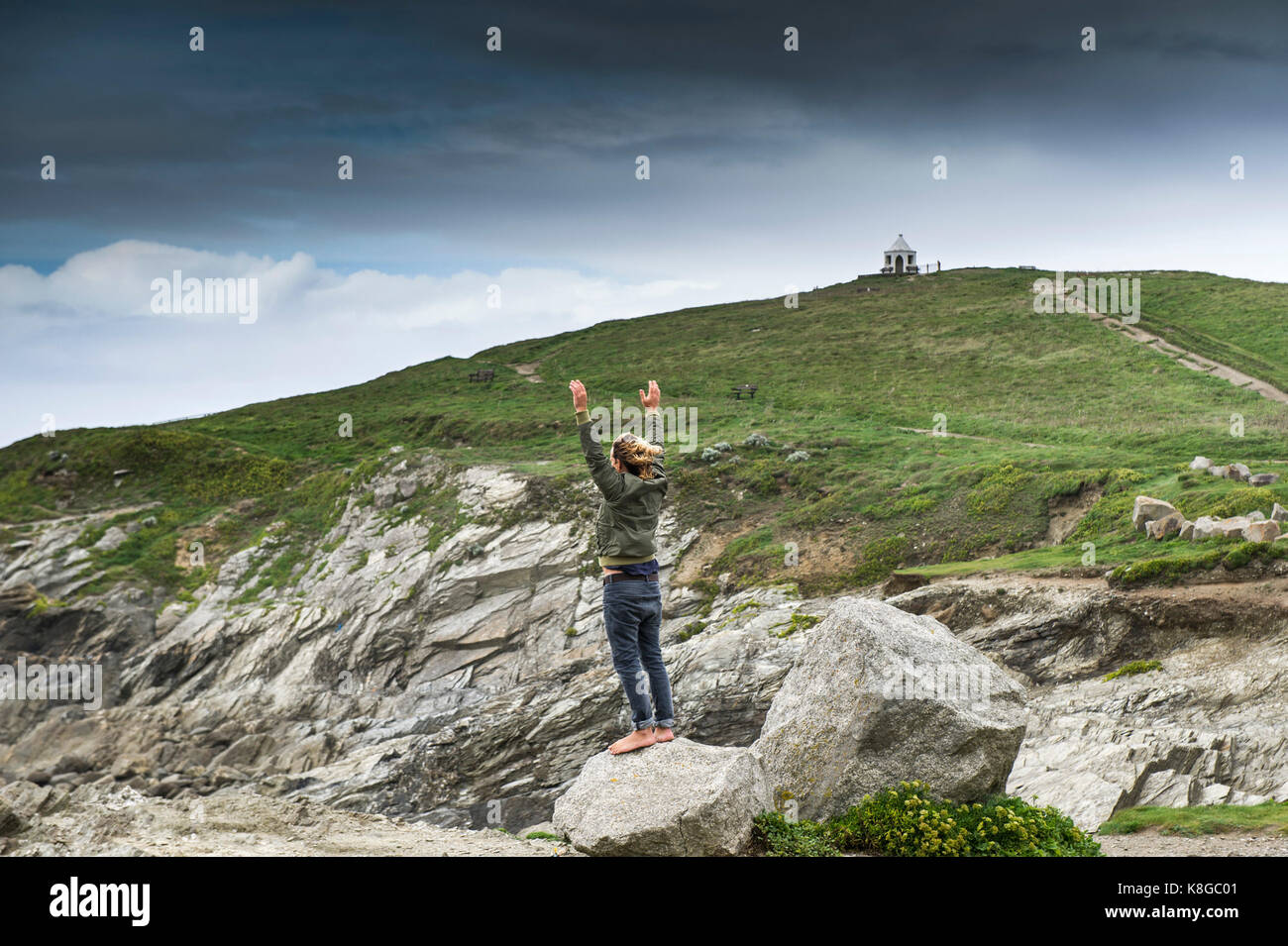 Newquay Cornwall - ein barfüssiger Mann, auf einem Stein und schwenkte seine Arme in der Luft zu wenig Fistral in Newquay, Cornwall. Stockfoto