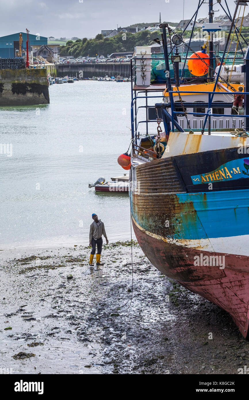 Padstow Hafen - ein Arbeiter Kontrolle der Rumpf des Fischtrawler Athena M in Padstow an der Küste von North Cornwall. Stockfoto