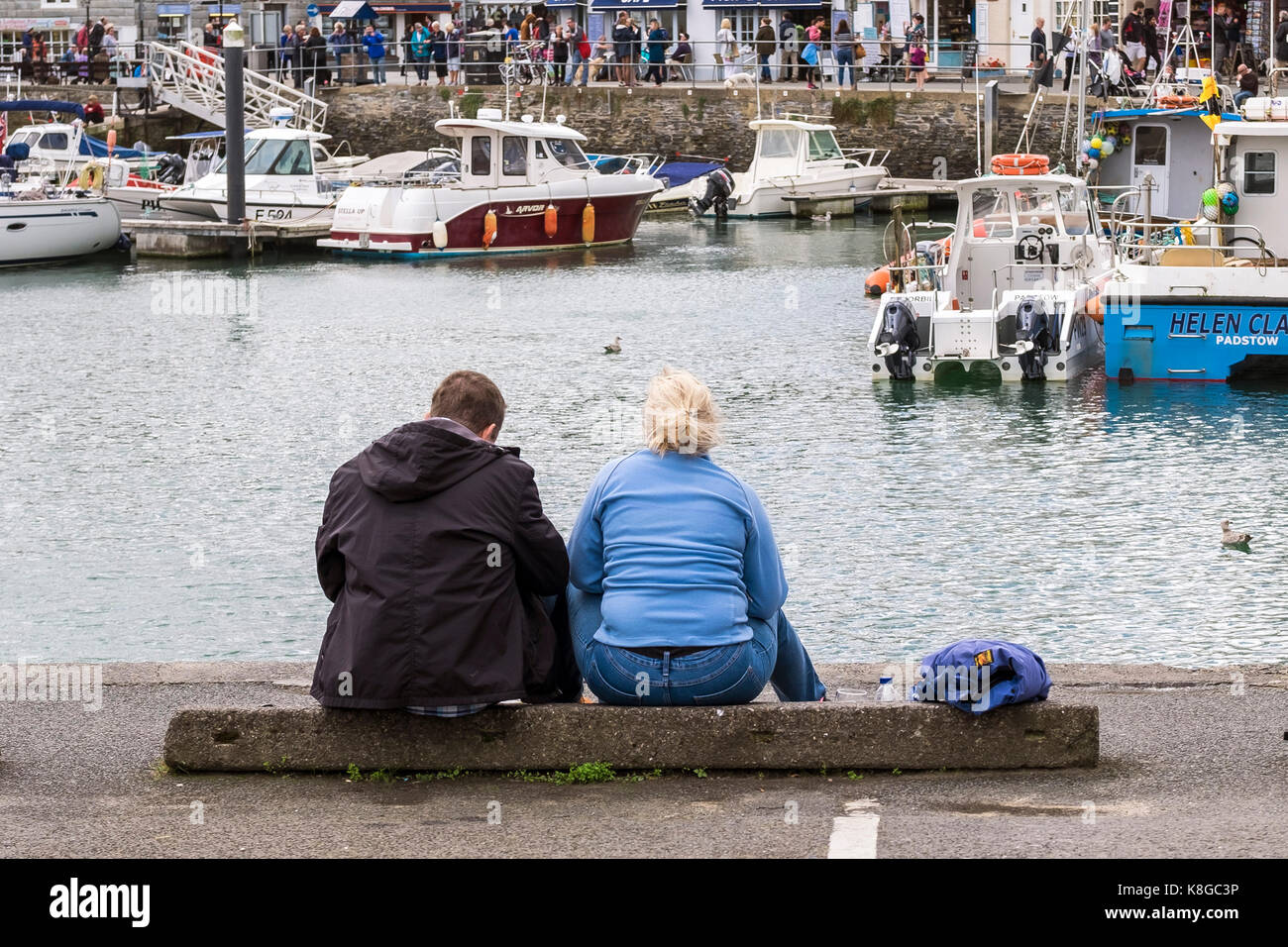 Urlauber - Urlauber sitzen und entspannen am Hafen in Padstow an der Küste von North Cornwall. Stockfoto