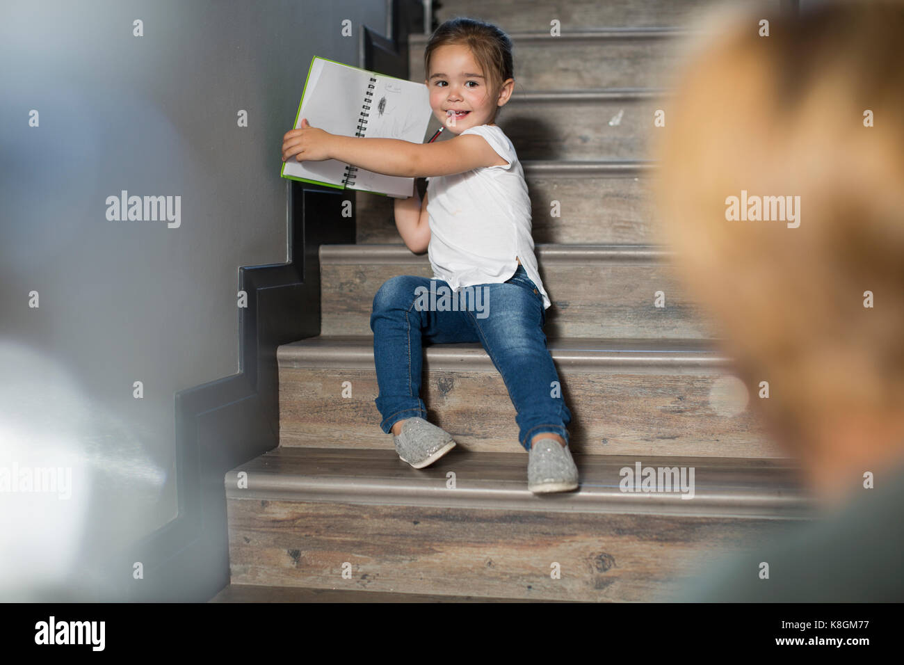 Mädchen auf der Treppe stolz zeigt Mutter Bleistift Zeichnungen Stockfoto