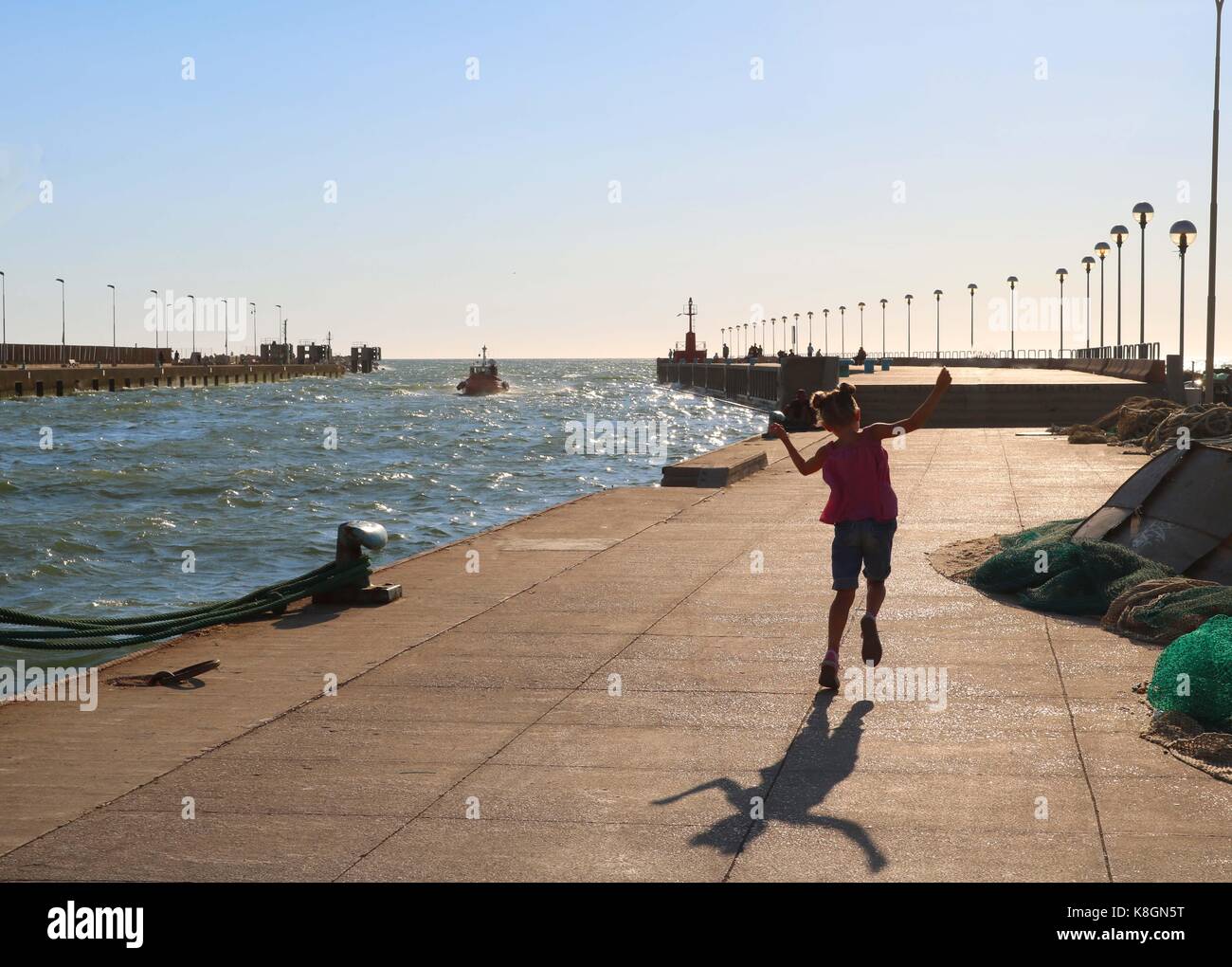 Girl skipping down Fishing Pier, Fiumicino, Rom, Italien Stockfoto