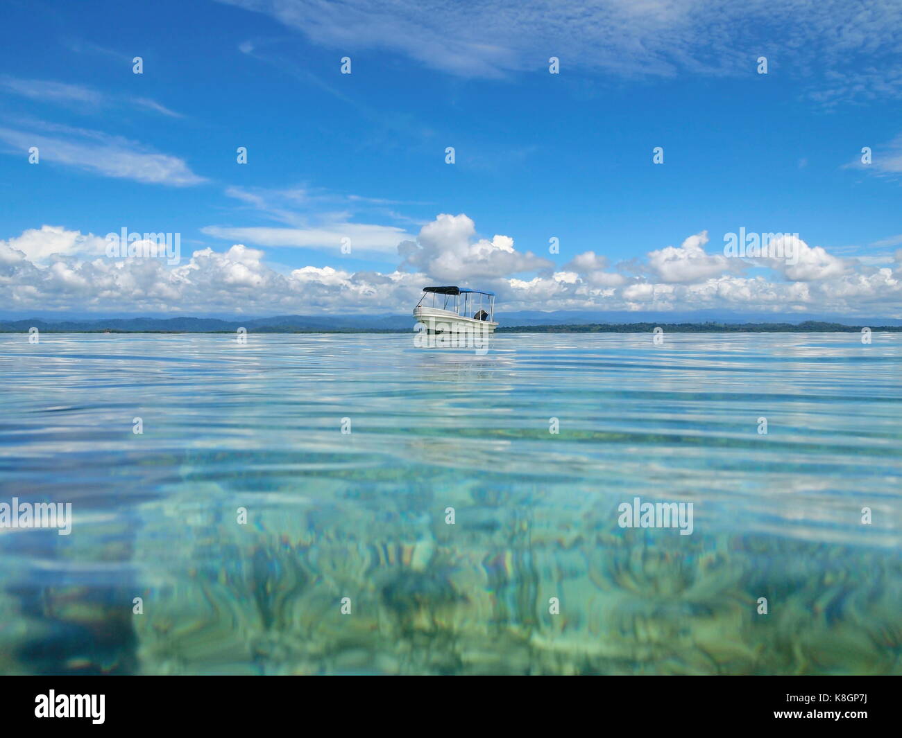Marine von ruhigen Wasseroberfläche ein Boot mit bewölkt blauer Himmel, Bocas del Toro, Karibik, Panama, Mittelamerika gesehen Stockfoto