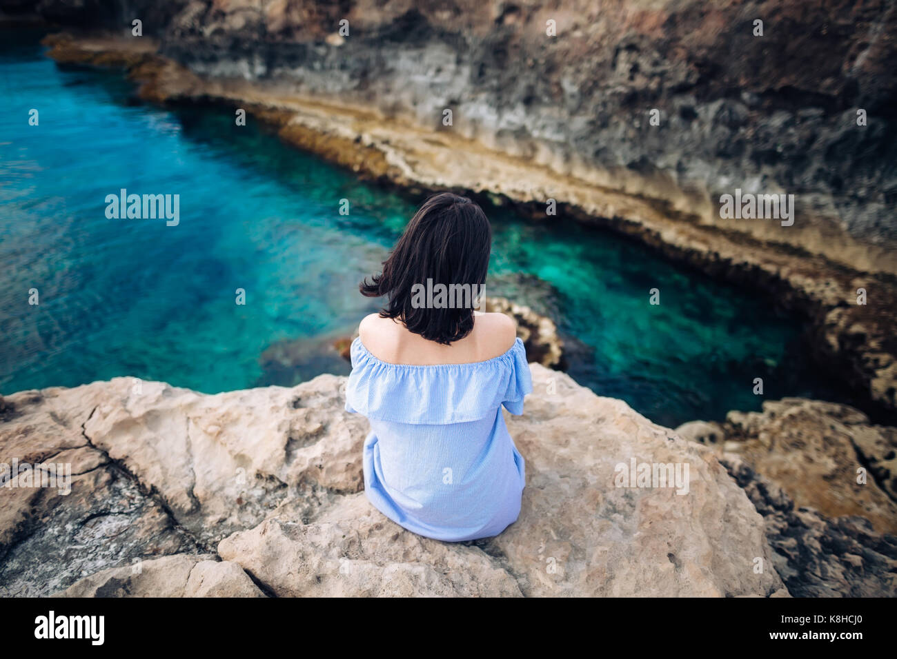 Junge Frau mit wunderschönem Meerblick am Kap Greco auf Zypern. Ansicht von hinten Stockfoto