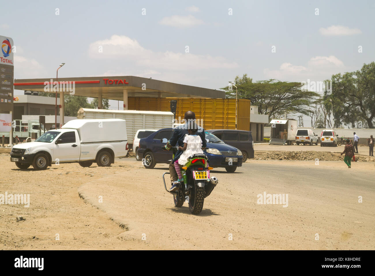 Kleines Mädchen reitet auf der Rückseite des Motorrad auf der belebten Straße, Nairobi, Kenia Stockfoto