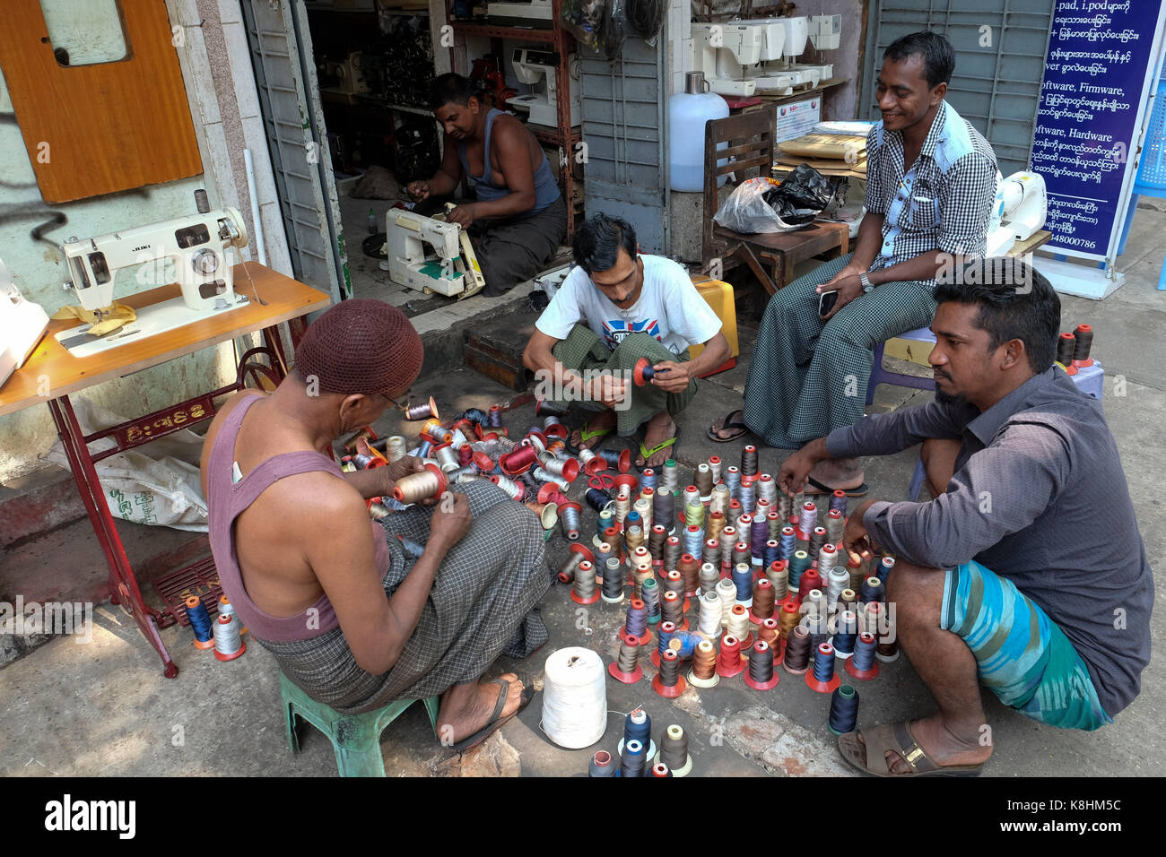 Burma, Myanmar: Schneiderei in einer Straße von Rangun. Männer in der Nähe von Rollen mit Gewinde Stockfoto