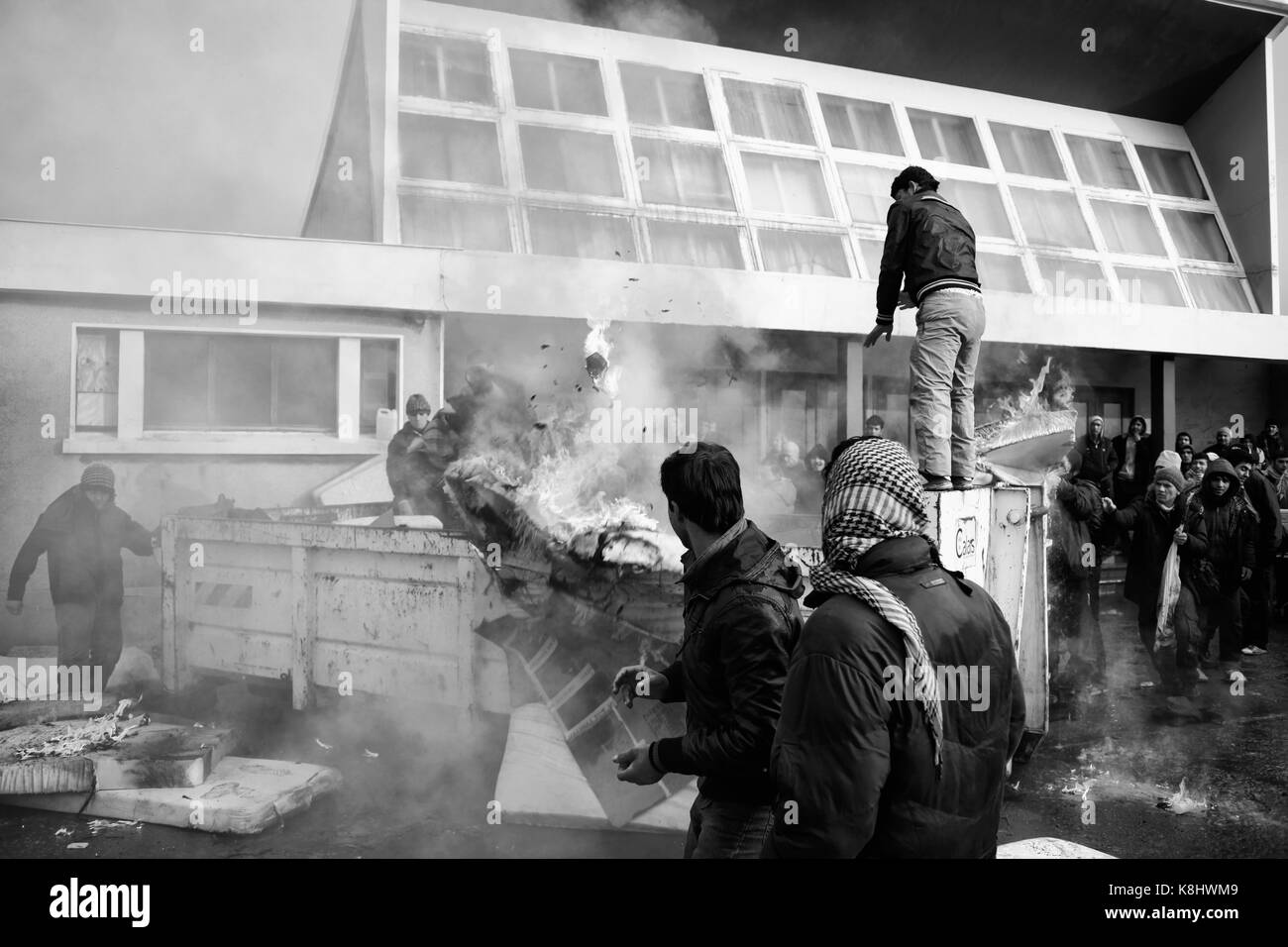 Nach der lokalen Behörden ein stillgelegtes Gymnasium ihren Besitzungen gelöscht, Asylbewerbern ein Müllcontainer steigen Sie aus Protest in Calais, Frankreich auf Januar Stockfoto