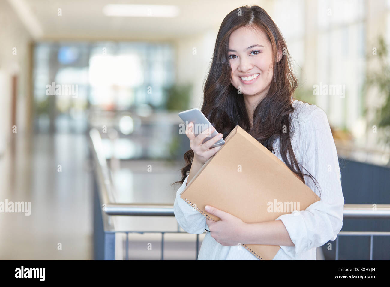 Asiatische student mit Smartphone lächelt glücklich in der Schule Stockfoto