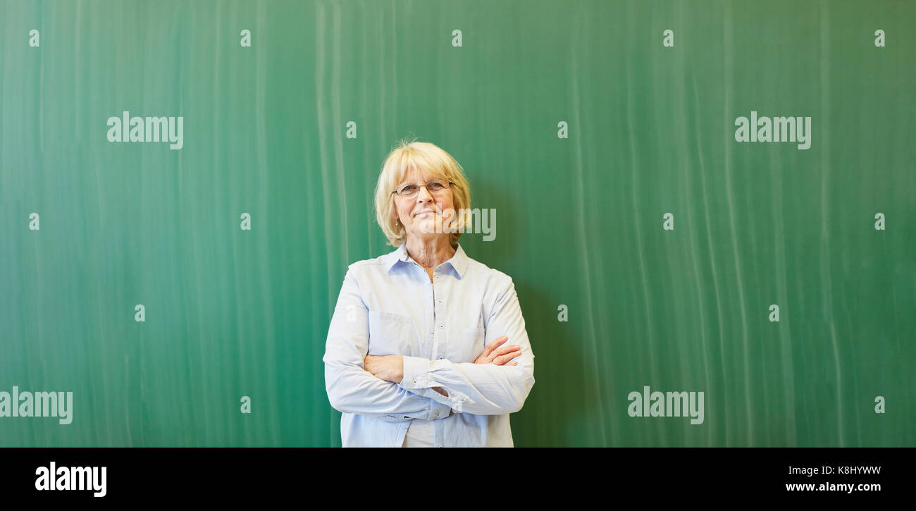 Ältere Frau als Dozent oder Lehrer vor der Tafel Stockfoto