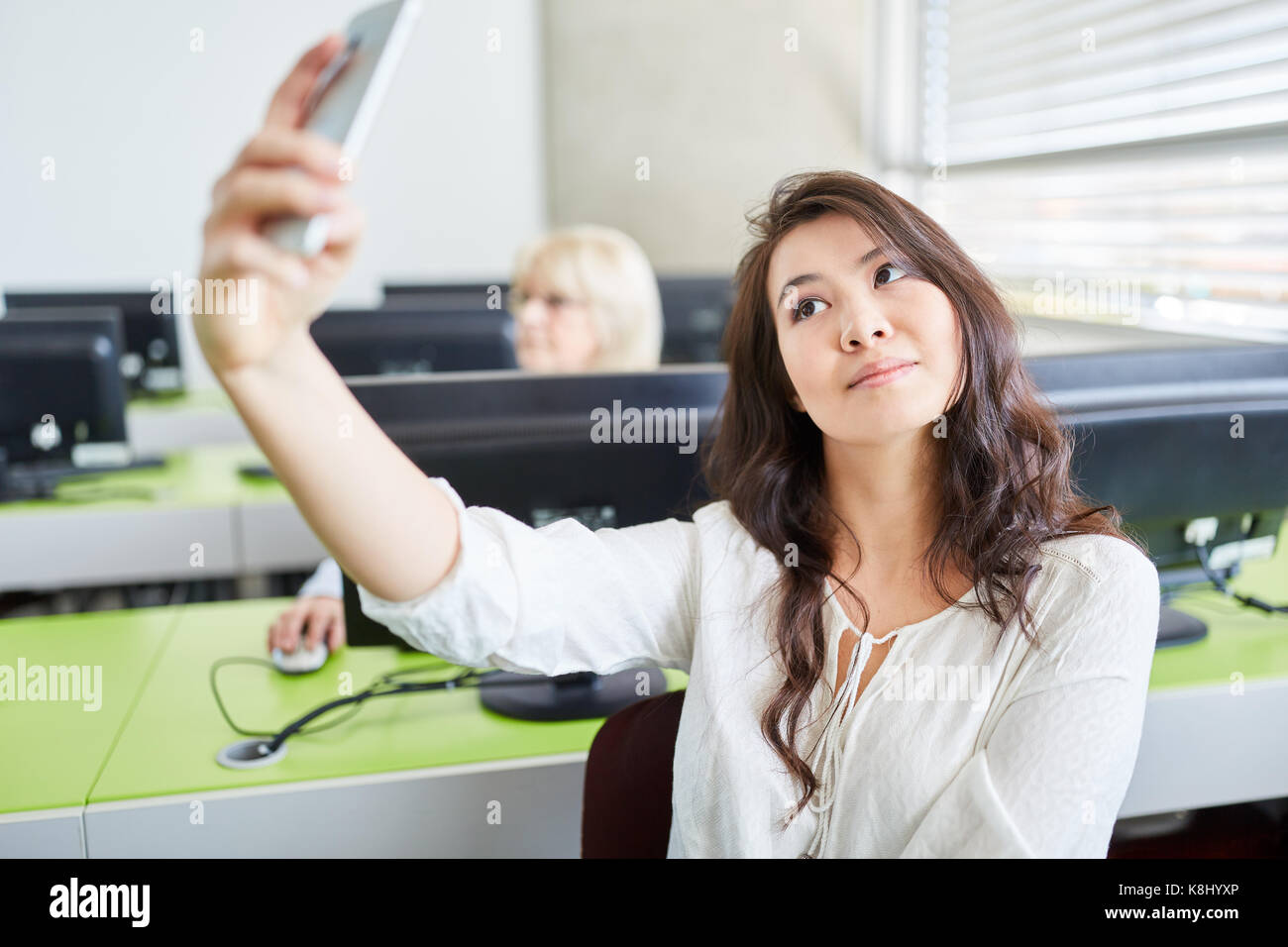 Asiatische Frau als Student nimmt selfie mit Smartphone in der Klasse Stockfoto