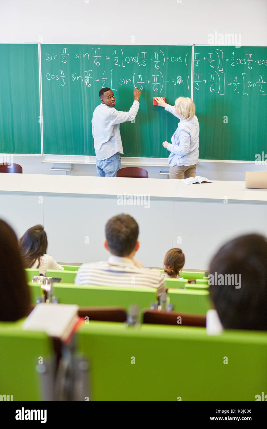 Schüler und Lehrer schreiben auf der Schiefertafel im Mathematikunterricht Stockfoto