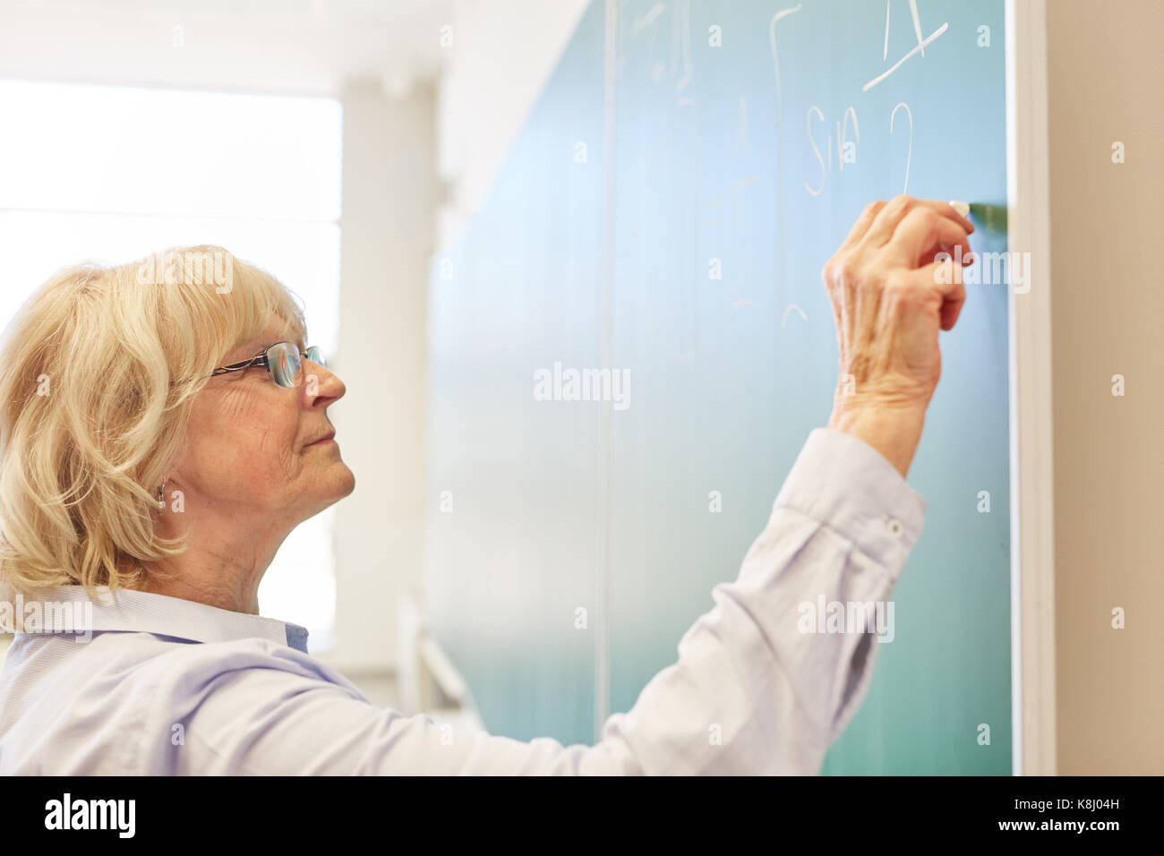 Ältere Frau als Dozent schreibt auf blackboard an der Universität Stockfoto