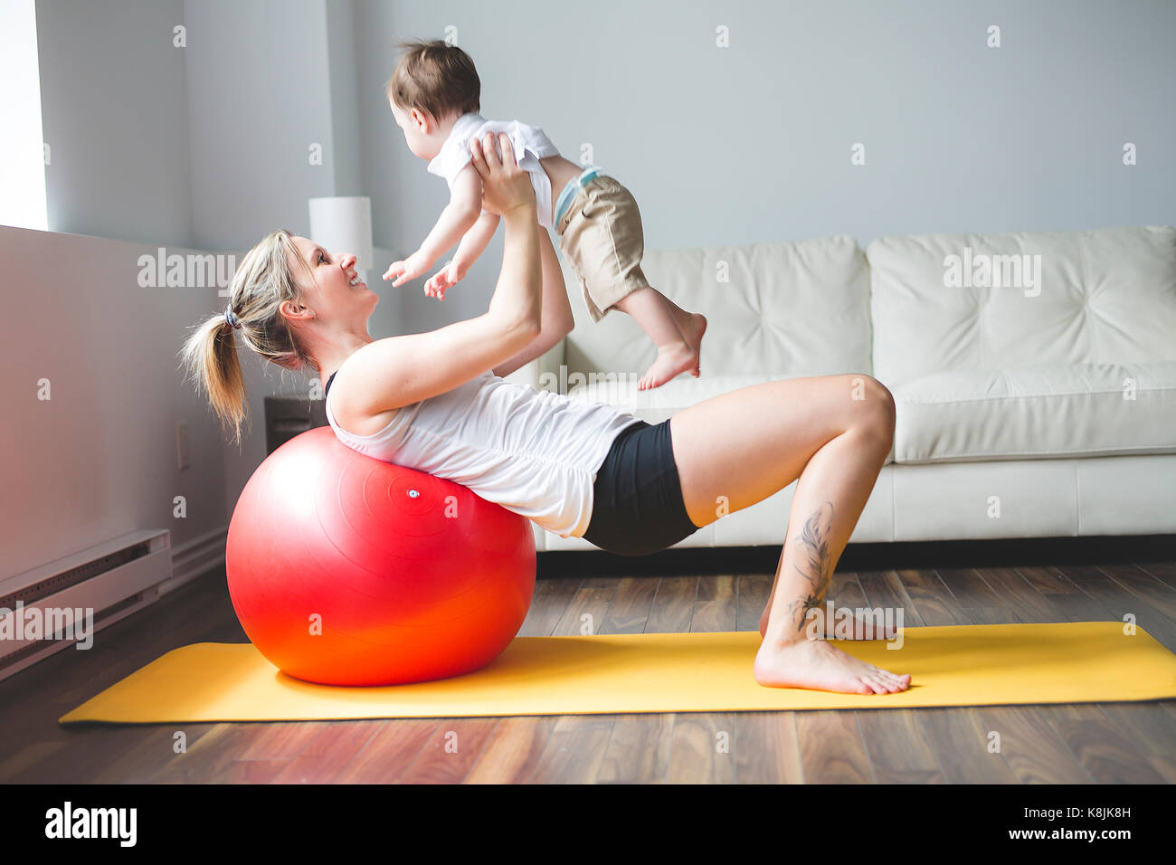 Sport Mutter ist in fitness und yoga mit Baby zu Hause eingeschaltet Stockfoto