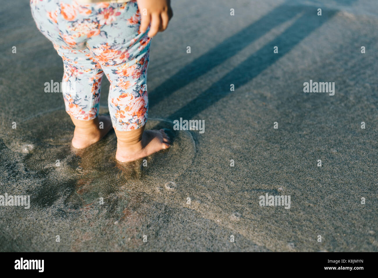 Baby spielt mit Wellen am Strand. Wachstum und Lernen Konzept. Familie und Parenting Konzept Stockfoto