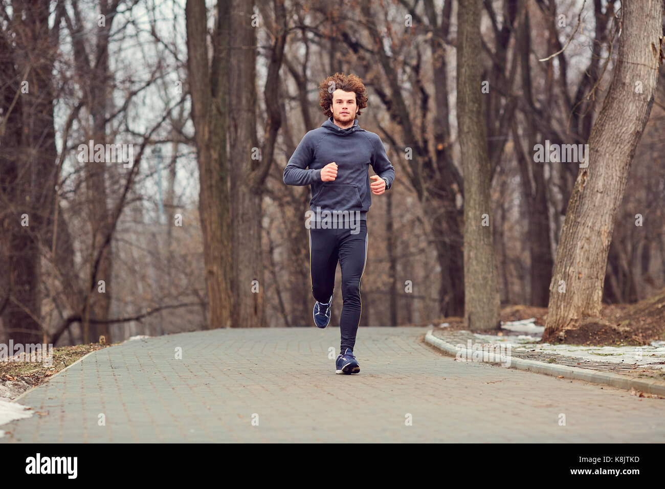 Eine junge männliche Läufer läuft in den Park. Stockfoto