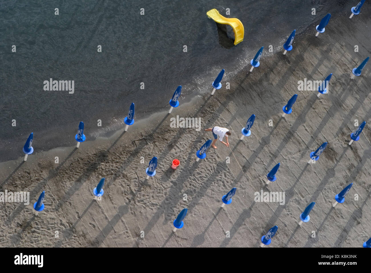 Strand Arbeiter fegt Sand und schließt sich für den nächsten Tag bereit, Sorrento, Italien Stockfoto