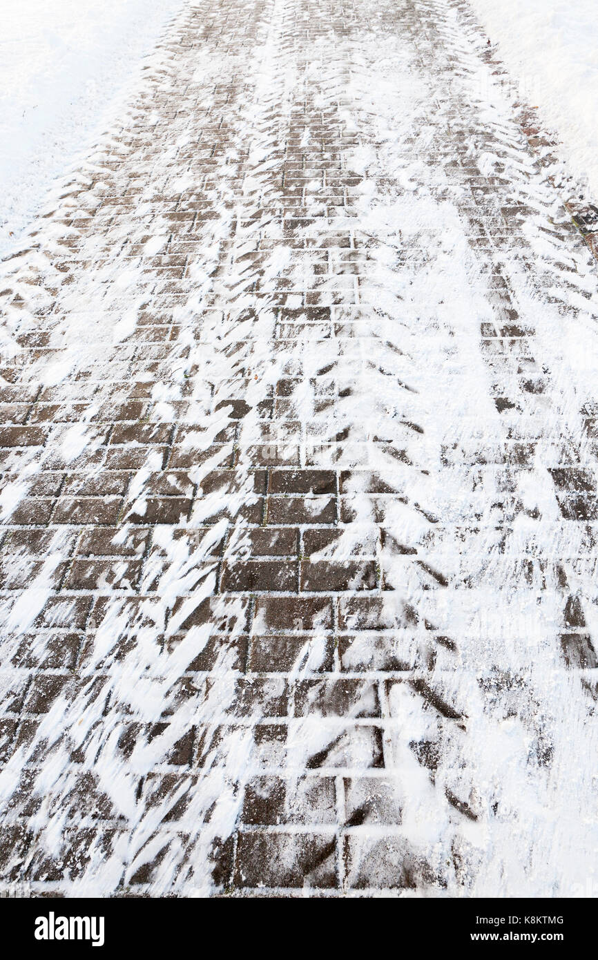 Pflastersteine in Dunkelbraun, mit Schnee bedeckt. Nahaufnahme fotografiert. Stockfoto