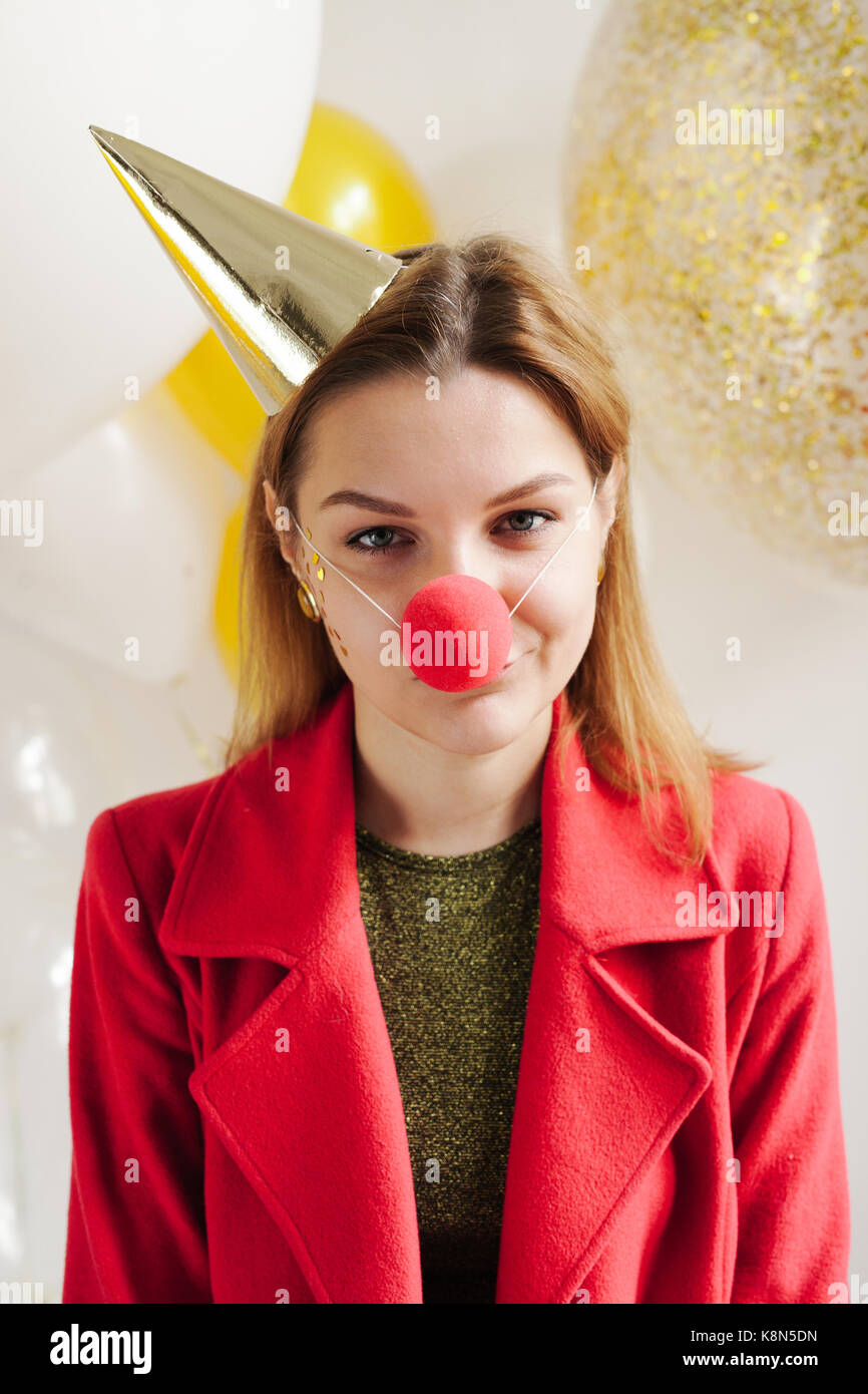 Junge Frau in einem feierlichen Kappe um Narren an einer Partei auf dem Hintergrund sinkender Konfetti Stockfoto