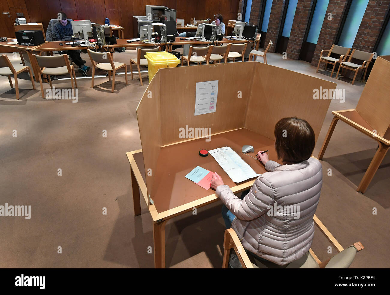 Langenhagen, Deutschland. 18 Sep, 2017. Eine Frau sitzt in einer Wahlkabine in einen Stimmzettel und Stimmen für die deutsche Bundestagswahl im Rathaus der Stadt Langenhagen, Deutschland, 18. September 2017. Zuvor hatte der Briefwahl Unterlagen wurden im Wahlbüro ausgestellt und weitergeleitet an die Wähler. Die Wähler in der Lage war, die Abstimmung über den Punkt in der Wahlkabine zu machen und den roten Umschlag in die Wahlurne werfen. Jeder Zeit und Transportrisiko unmöglich gemacht, dabei. Quelle: Holger Hollemann/dpa/Alamy leben Nachrichten Stockfoto