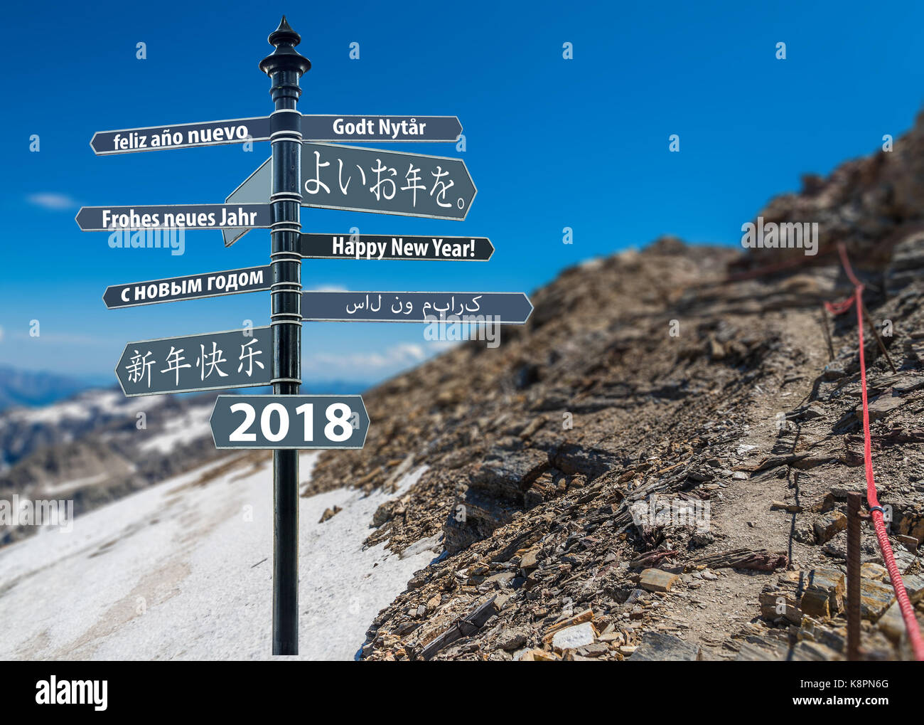 Wegweiser whit Frohes neues Jahr in vielen Sprachen, Berg im Hintergrund Stockfoto