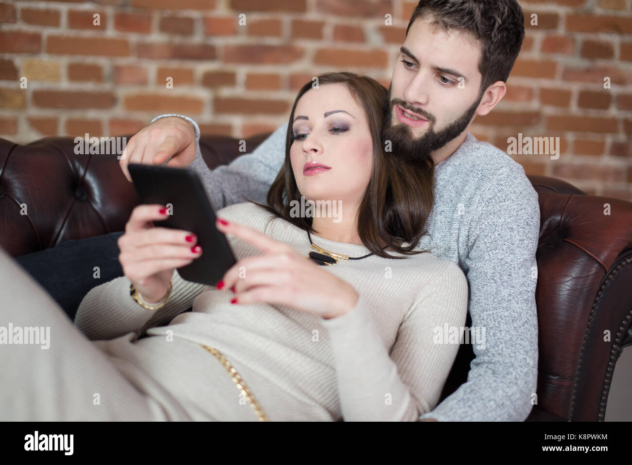 Junges Paar on-line-Einkaufen durch digitale Tablet, liegend auf dem Sofa indoor Stockfoto