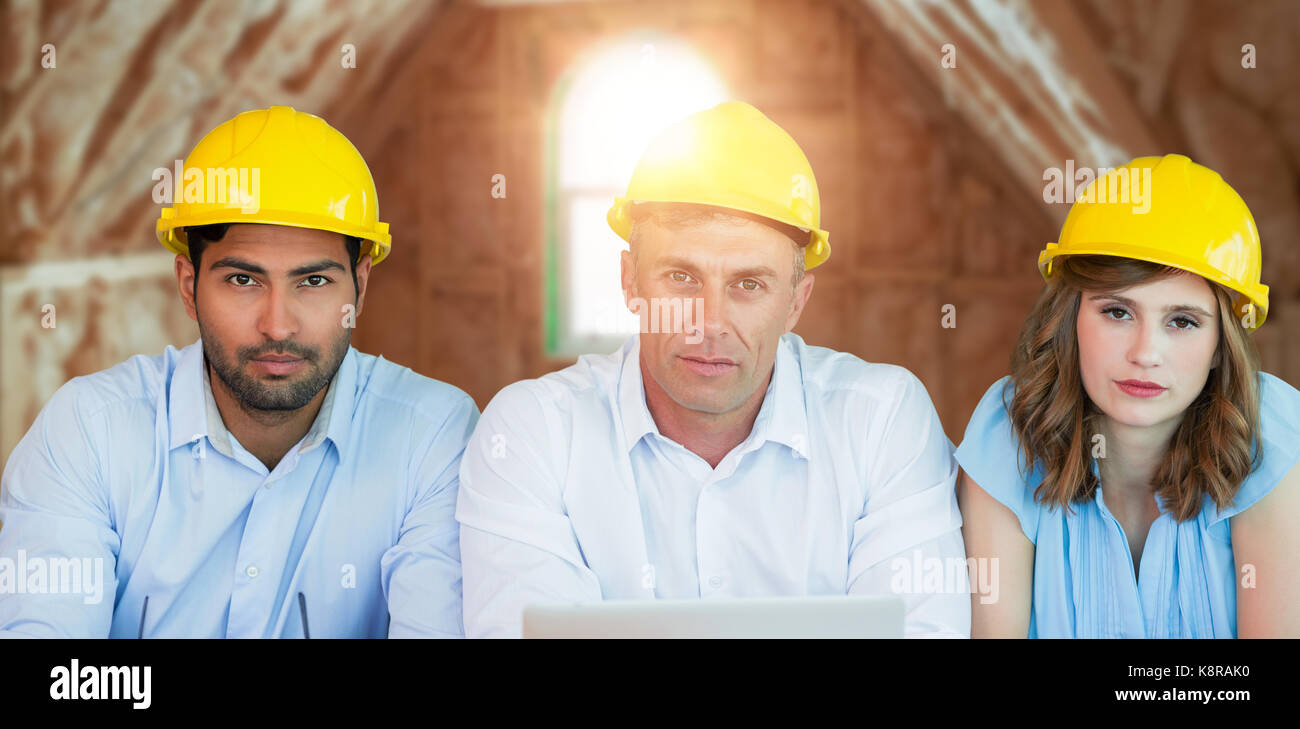 Porträt des Architekten hardhats tragen beim Sitzen am Tisch gegen Zimmer in Haus im Bau Stockfoto