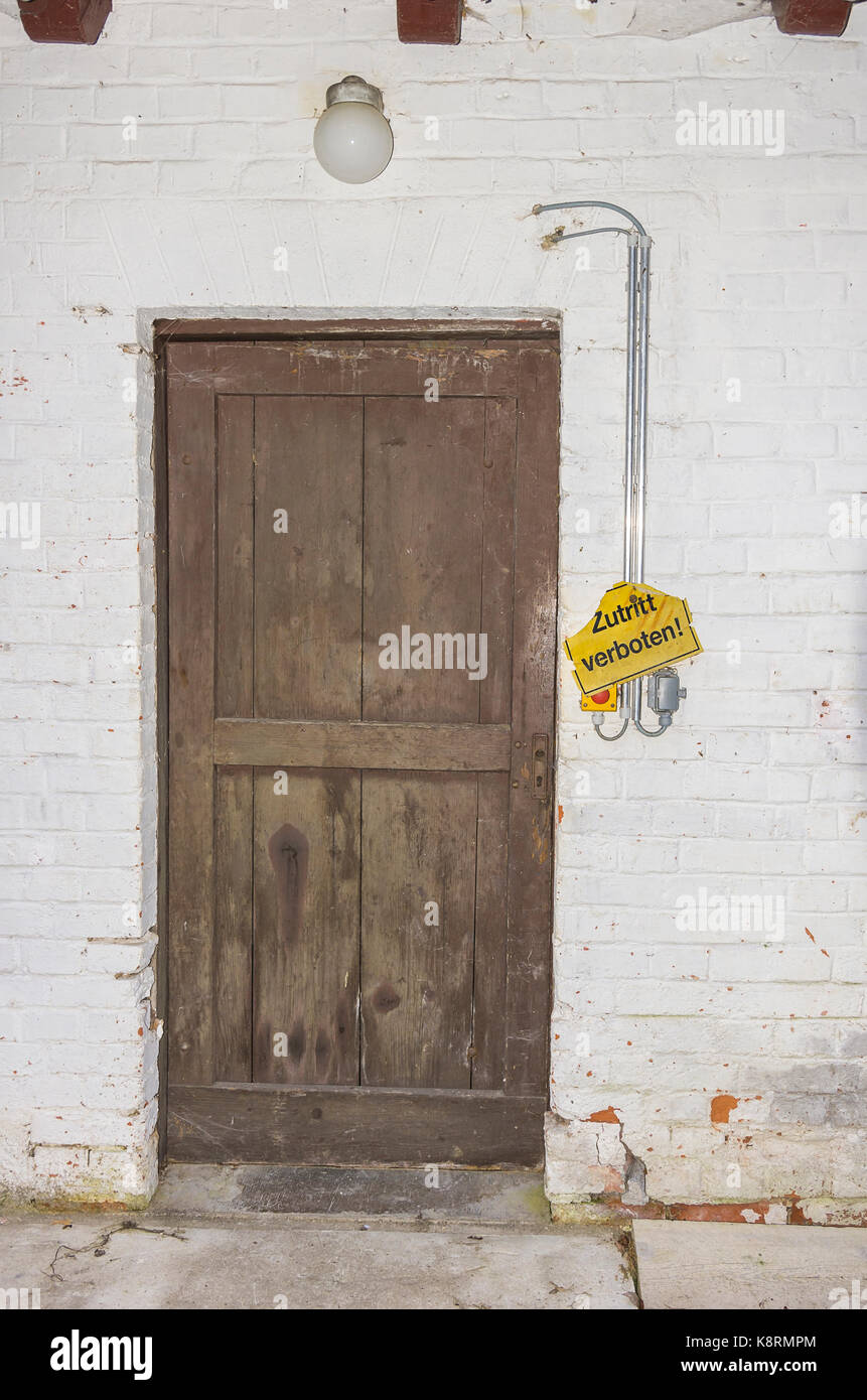 Schild 'Eintritt verboten' in deutscher Sprache neben einer Tür zu einem alten historischen Fabrikgebäude. Stockfoto