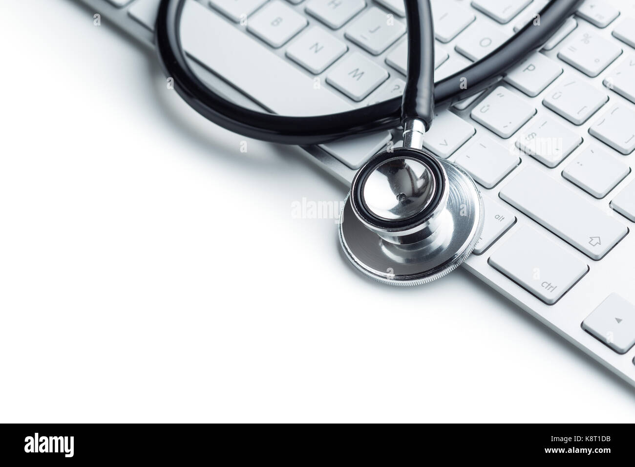 Medizinische Stethoskop auf dem Computer Tastatur auf weißem Hintergrund. Schwarz Stethoskop. Gesundheit Konzept. Stockfoto